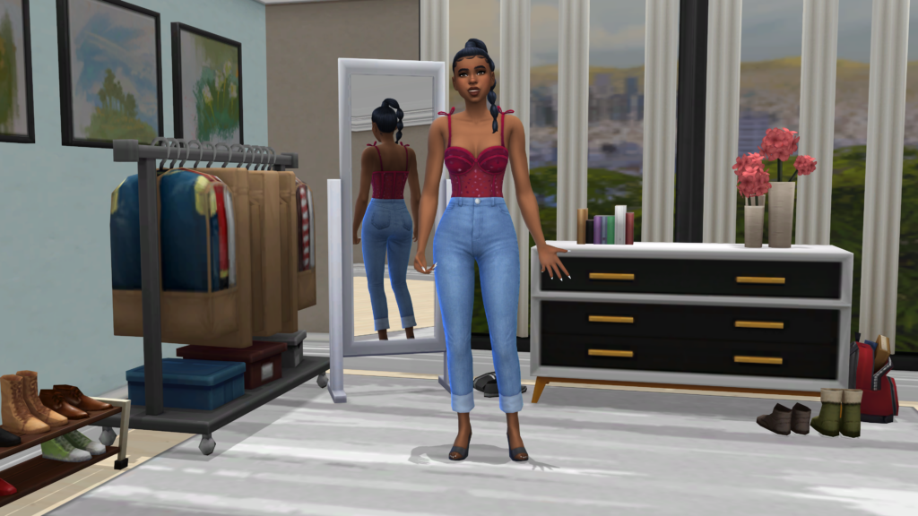 Un sim con pantalones vaqueros azules de talle alto y un corsé rojo con el cabello recogido en una trenza. Este sim está de pie en un dormitorio donde hay un espejo, una cómoda y un perchero de ropa.