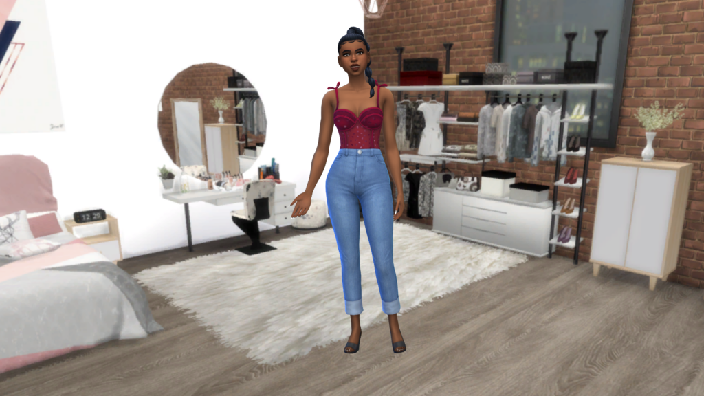 Un sim con pantalones vaqueros azules de talle alto y un body de corsé rojo con el cabello recogido en una trenza. Este sim está de pie sobre un suelo de madera con una alfombra peluda, en esa habitación hay una mesa de tocador y una cómoda.